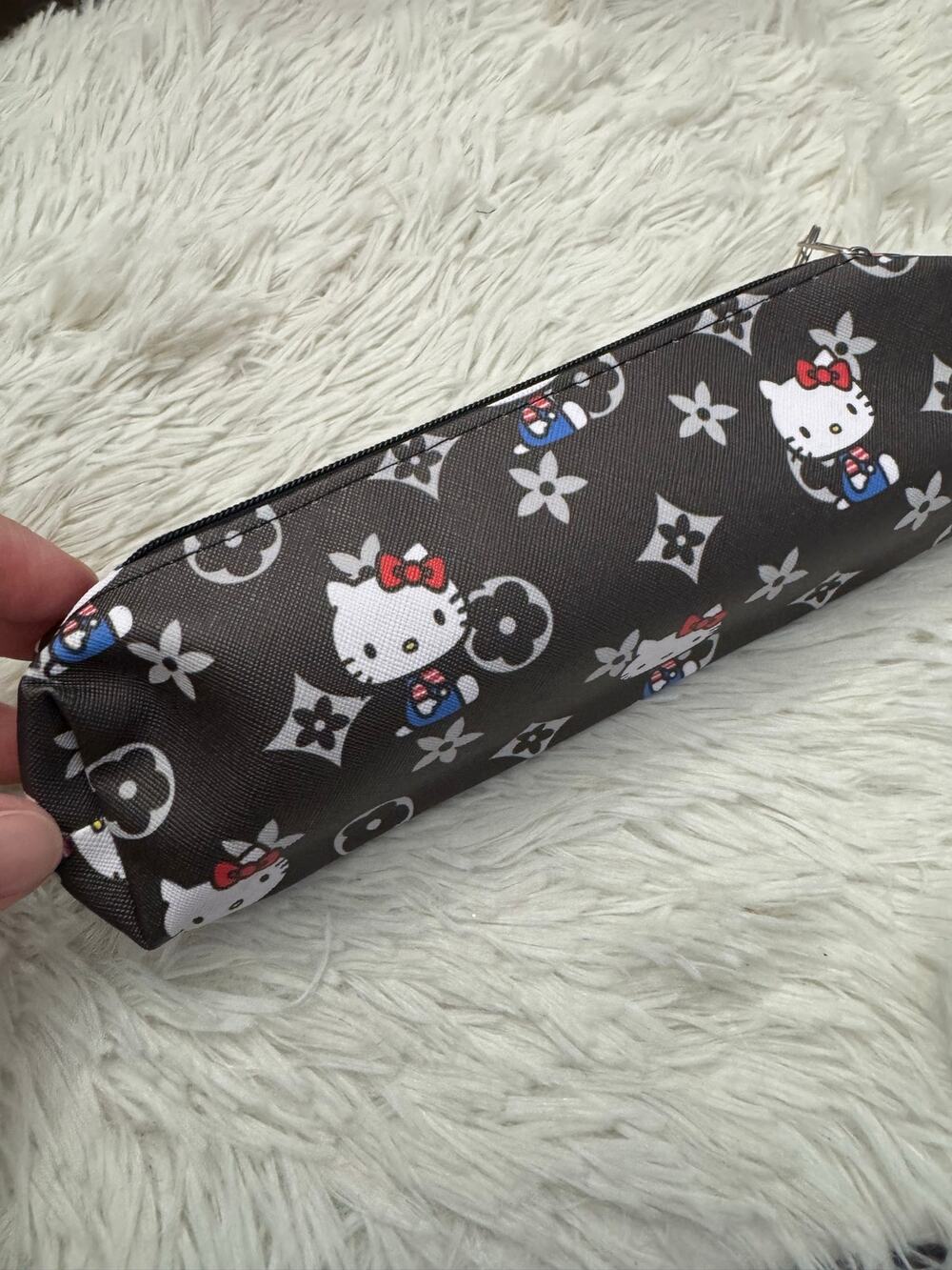 Hello Kitty pencil case with red bows on a dark background with floral motifs